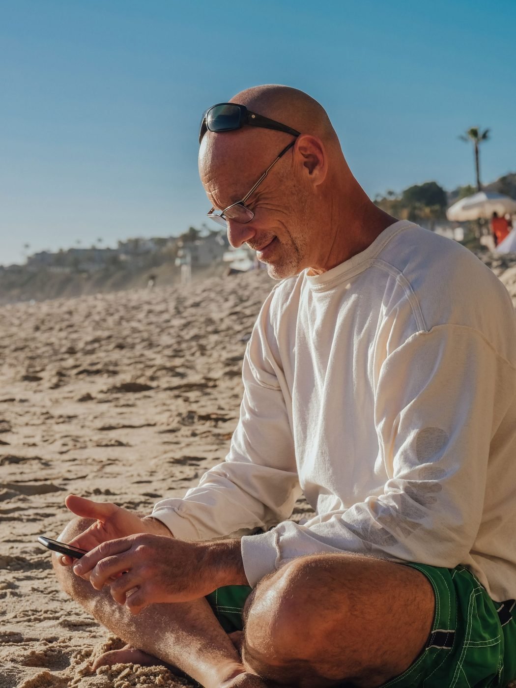 Empresário sorrindo na praia, acompanhando os números da empresa pelo celular
